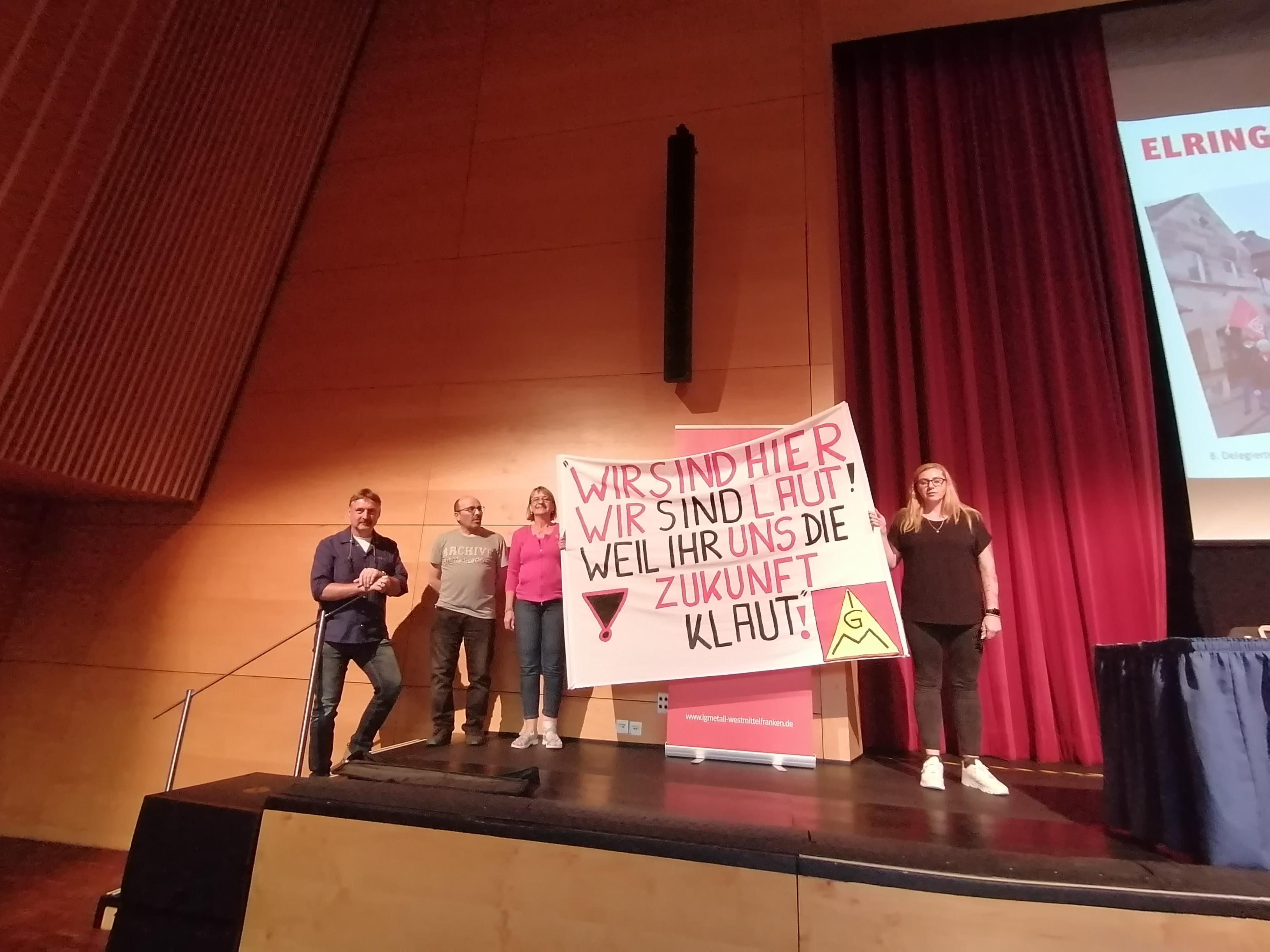 Kolleg*innen der Firma Elring-Klinger halten ein Transparent mit der Aufschrift: "Wir sind hier, wir sind laut, weil ihr uns die Zukunft klaut!" 