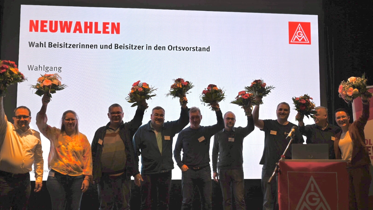 Der neu gewählte Ortsvorstand der IG Metall Westmittelfranken steht nach der Wahl mit Blumen auf der Bühne und jubelt.