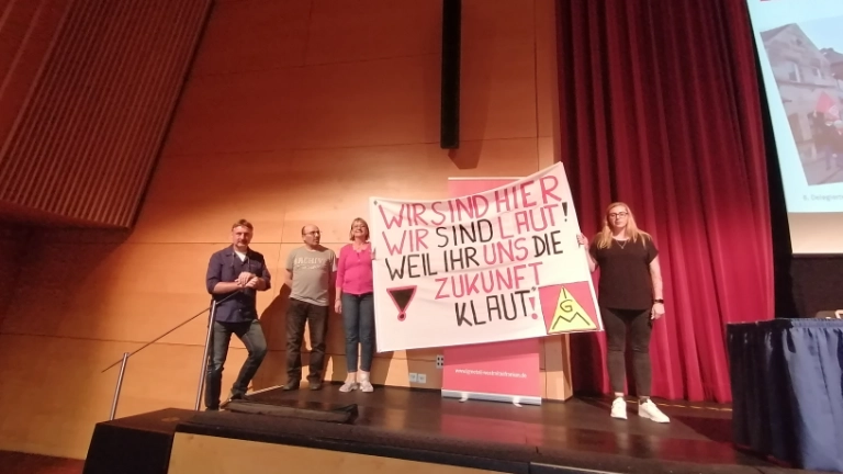 Kolleg*innen der Firma Elring-Klinger halten ein Transparent mit der Aufschrift: "Wir sind hier, wir sind laut, weil ihr uns die Zukunft klaut!" 