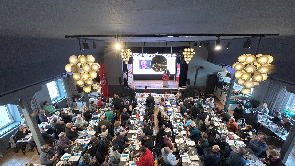 Das Plenum der Delegiertenversammlung Westmittelfranken sitzt in einem festlichen Saal und hört den Reden zu.